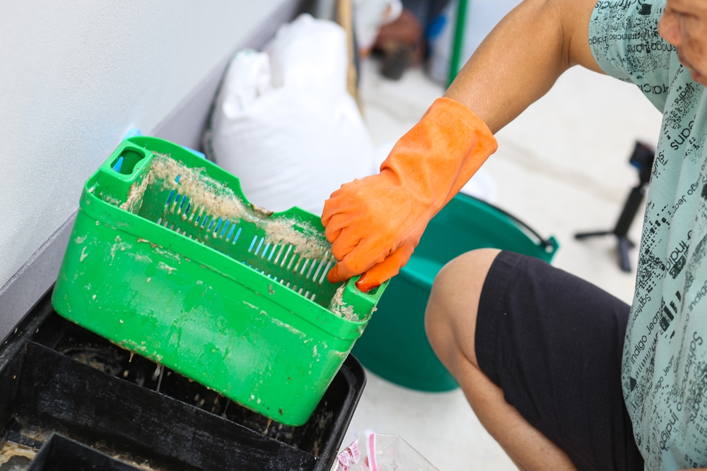 A,Man,Cleaning,A,Grease,Traps,Box,Outside,The,House,